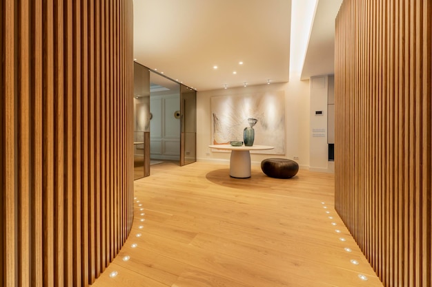 Hallway of a house with walls covered with latticework of vertical wooden slats lamps on the light oak wood floor