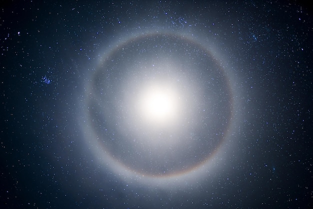 Halo from the moon in the starry sky at night A lunar halo around the Moon showing several color