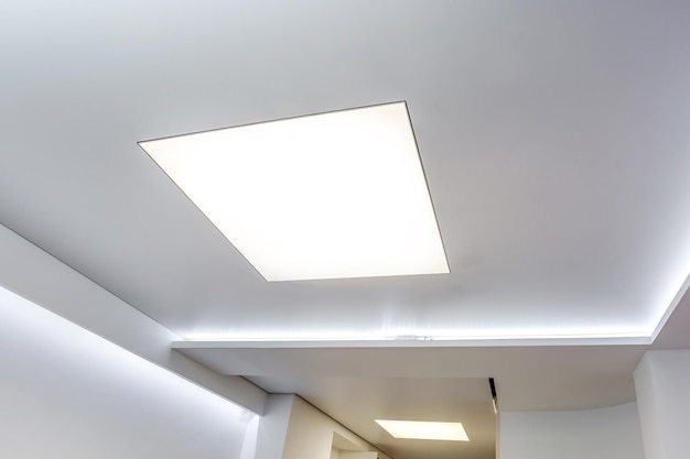 Halogen spots lamps on suspended ceiling and drywall construction in in empty room in apartment or house Stretch ceiling white and complex shape