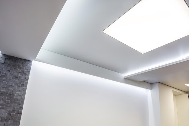 Halogen spots lamps on suspended ceiling and drywall construction in in empty room in apartment or house Stretch ceiling white and complex shape