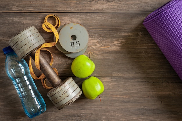 Halters, sportmat, tablet op een houten ondergrond. Het concept van fitness en gezondheid. Bovenaanzicht met een ruimte voor tekst.