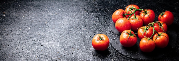 Halve en hele tomaten op een tak op een stenen bord