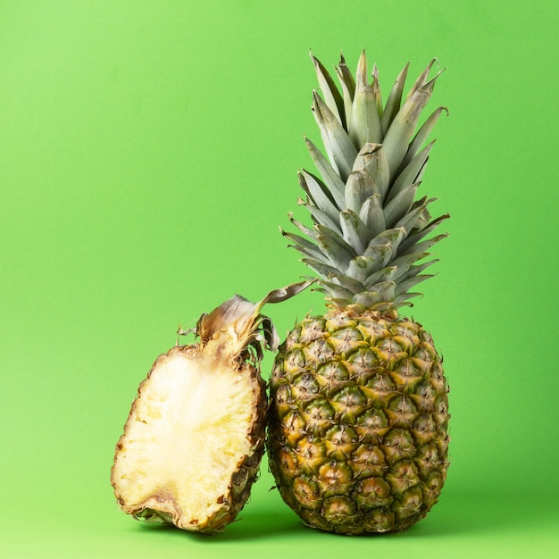 Halve en hele verse ananas op groene achtergrond.