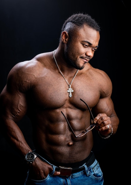 Halve grootte portret van knappe Afro-Amerikaanse man met naakte torso Studio foto van bodybuilder met bril in handen Gezond lichaamsconcept