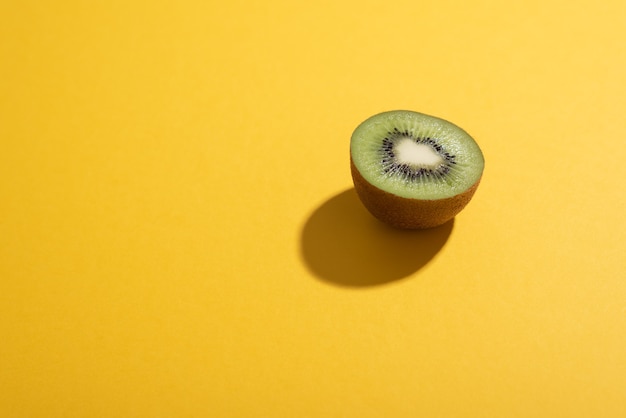 Halve kiwi over kleurrijk vlak bureau met hard zonlicht