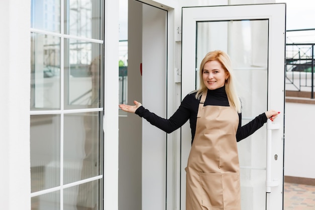 Halve lengte portret van serveerster gekleed in schort met kopie ruimte voor merknaam open winkel begint te werken klaar om bezoekers te bedienen, vrouwelijke ondernemer barista staande bij de ingang van het restaurant