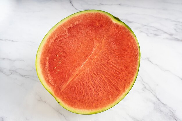 Halve watermeloen geïsoleerd op een witte marmeren achtergrond