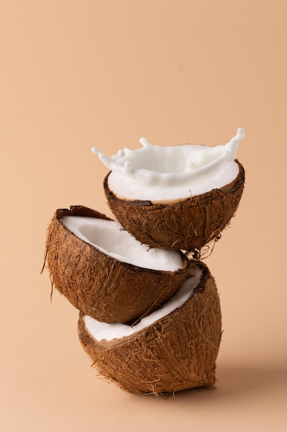 Halved coconut with milk splash creative composition with\
coconuts and milk