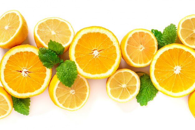 Половинки лимонов и апельсинов лежат в ряд, вид сверху. Цитрусы и листья мяты для приготовления лимонада, копией пространства.