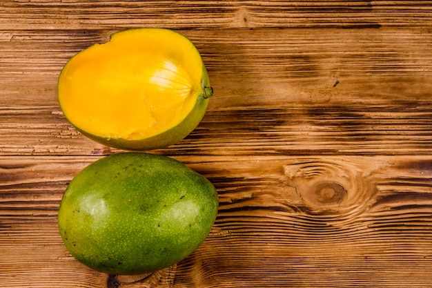 Halved mango fruit on rustic wooden table. Top view