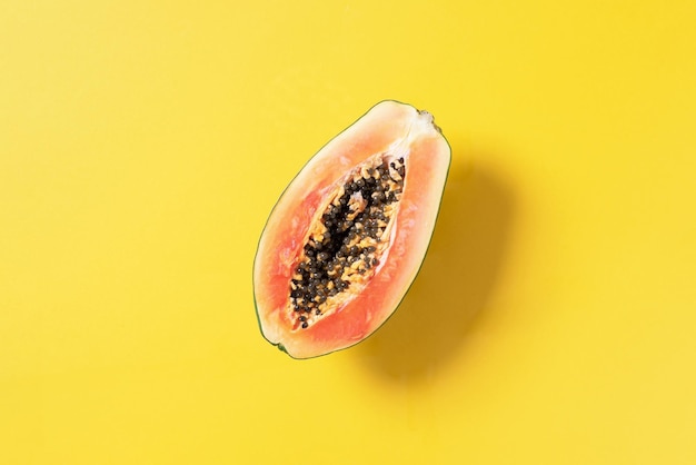 Halved papaya on yellow background Top view Copy space Summer time Tropical travel exotic fruit Vegan and vegetarian concept