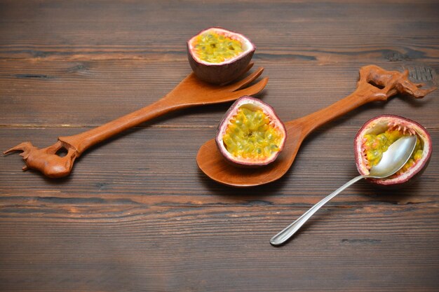 Halved passion fruit and spoon on wooden background