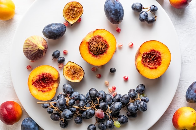 Halved peaches with nectarines and grapes on white plate