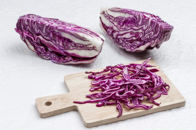 Halved red cabbage, sliced cabbage on cutting board. Fresh vegan food.  White background.