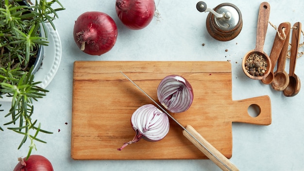 Halved red onion on wooden kitchen cutting board, top view