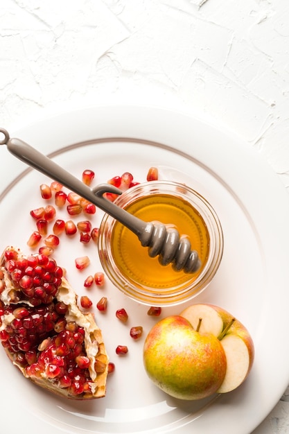 Photo halves of apples with honey pomegranate seeds on a large plate vertical