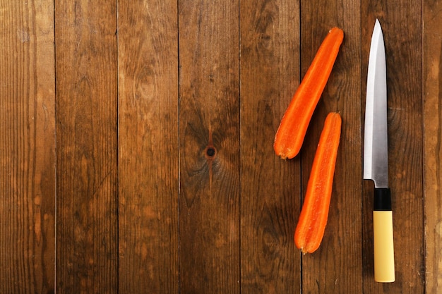 Halves of carrot with knife on wooden background