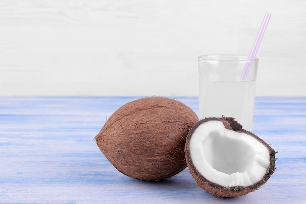 Halves of coconut and coconut milk on a blue wooden table and on a white background with a place for writing