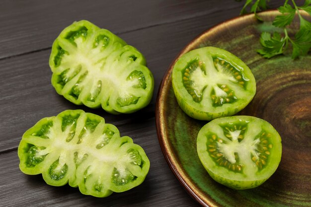 Halves of green tomatoes in a plate and on the table