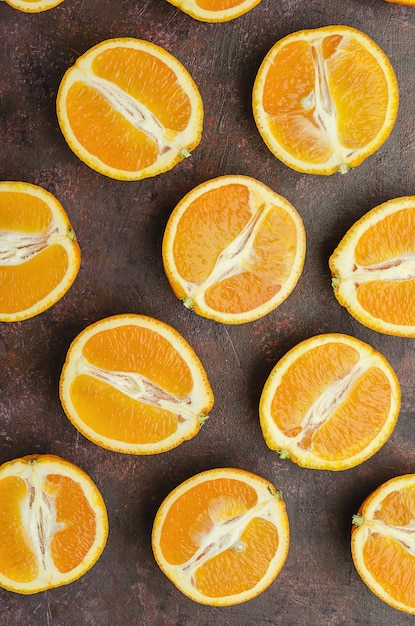 Halves of oranges on a dark brown background.