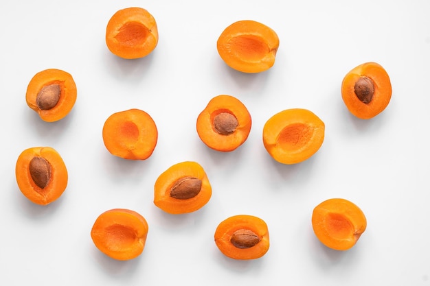 halves of pitted and pitted apricots lie on a light background in random order, top view