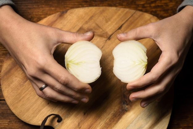 Halves of a raw onion in the hands of a woman on a wooden background