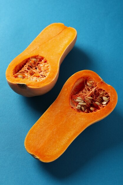 Halves of raw pumpkin on blue background