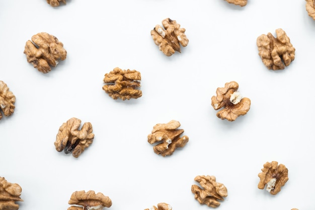 Halves of walnuts on white background pattern top view