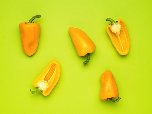 Halves and whole fruits of Bulgarian pepper on a green background. Vegetarian food.