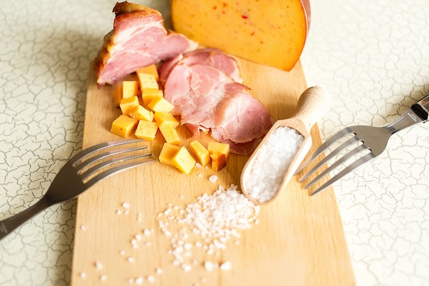 Ham, cheese, bread and salt on a wooden cutting board