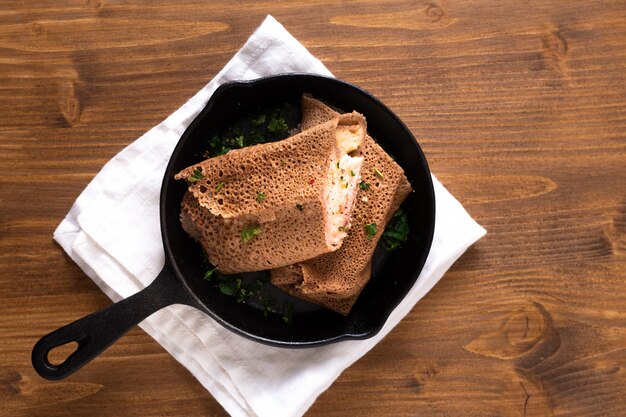 Ham and Cheese Crepe in iron skillet cast on wood background