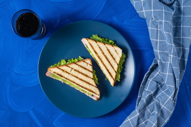 Ham en greens sandwich op een blauwe achtergrond.