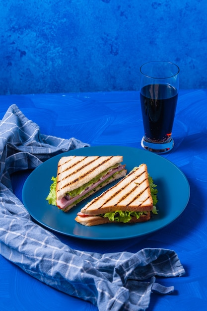 파란색 표면에 햄과 채소 샌드위치입니다.