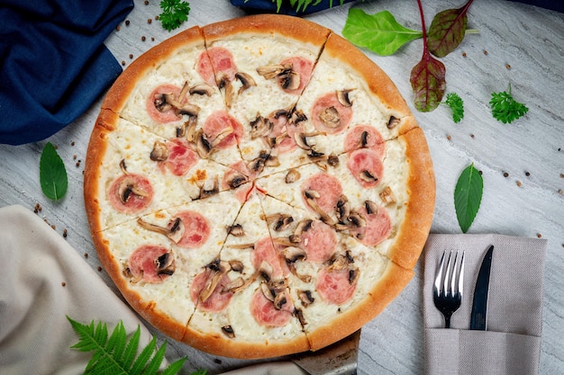 Ham and mushroom pizza on a spatula freshly baked with parmesan\
cream sauce ham and mushrooms