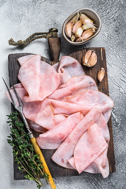 Ham Thin sliced on wooden cutting board with herbs. White background. Top view.
