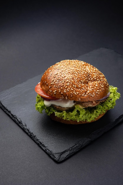 Hamburger on a black board on a black wooden background