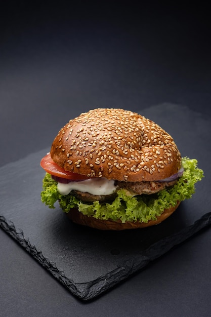 Hamburger on a black board on a black wooden background