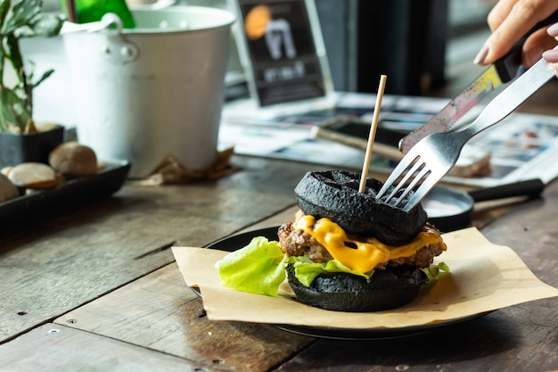 Hamburger black pork on the plate on a wooden table.