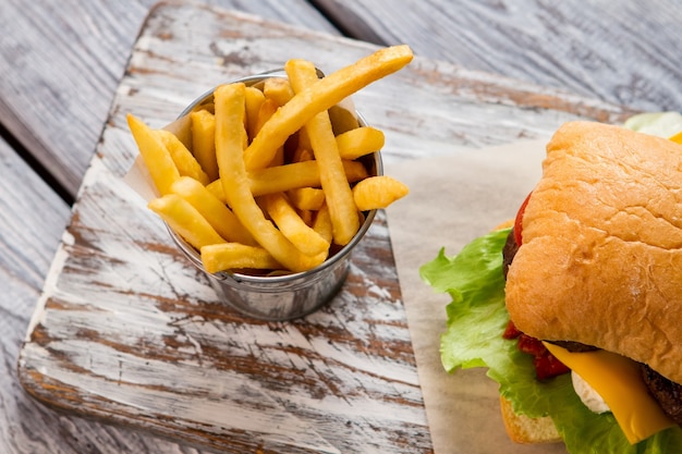 Hamburger en emmer met frietjes. Bovenaanzicht van frietjes. Lekker gegeten in eetgelegenheid. Zo vers en knapperig.