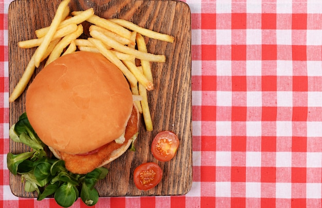 Hamburger, Franse frietjes en tomaat op tafelblad bekijken