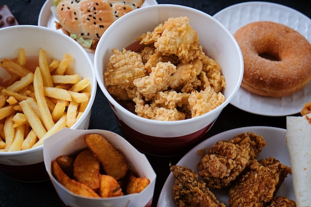 hamburger, french fries, donut, nuggets and chocolate on black