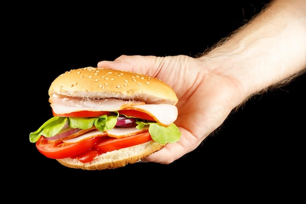 Hamburger in de hand isoleren op zwart