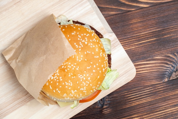 Hamburger in papier en op een lichte boord verbrand houten bovenaanzicht