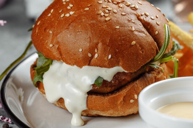 Hamburger met friet en saus op een witte plaat.