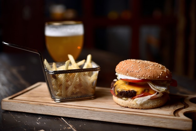 Hamburger met frietjes en bier op een houten bord