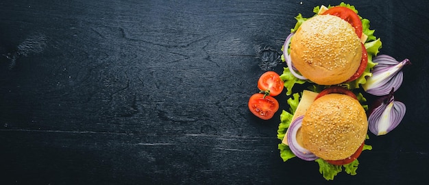 Hamburger met kaas vlees tomaten en uien en kruiden op houten achtergrond bovenaanzicht vrije ruimte