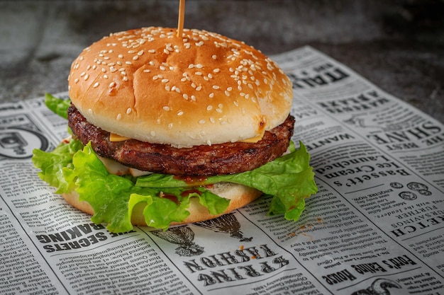 Hamburger met kotelet en sla in een sesambroodje op een grijze stenen ondergrond