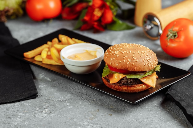 Hamburger met kotelet, kaas en tomaten. met patat en hamburgersaus