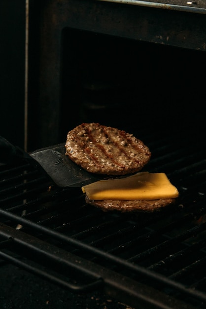 Hamburger vlees bereiden met kaas op de grill zwarte achtergrond