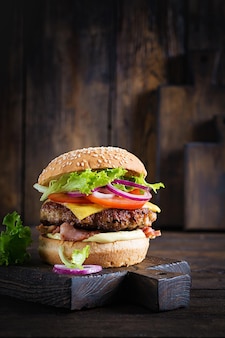 Hamburger con pancetta, carne di hamburger di tacchino, formaggio, pomodoro e lattuga su fondo di legno. hamburger gustoso. avvicinamento